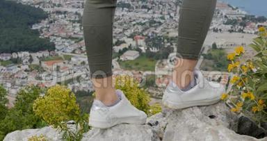 女徒步旅行者的双腿站在山顶岩石上
